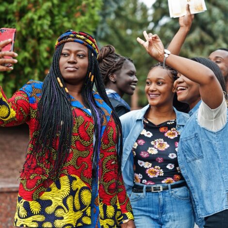 Group of five african college students spending time together on Group of five african college students spending time together on campus at university yard. Black afro friends making selfie on phone. Education theme.